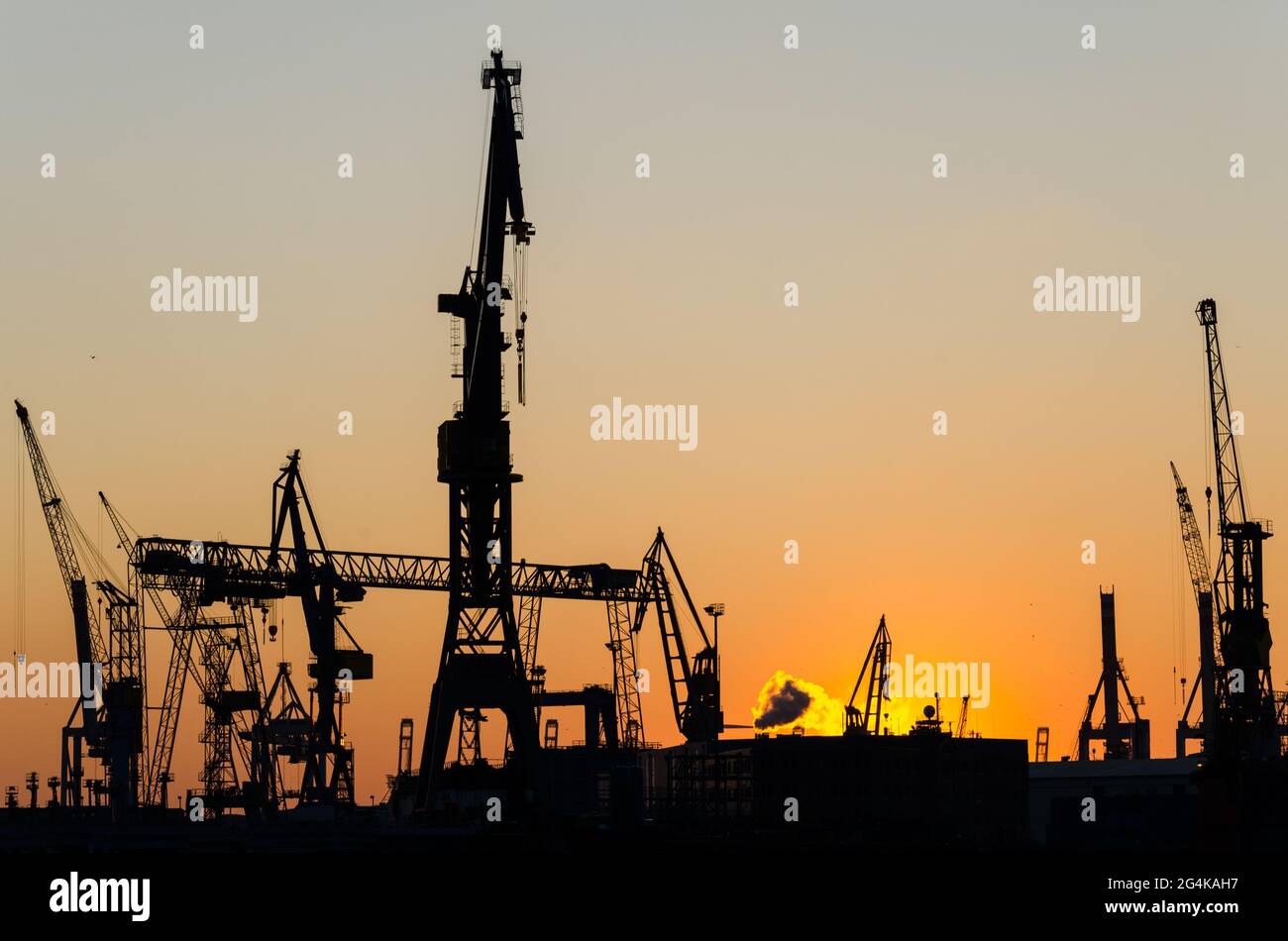 Silhouette of harbour cranes and container terminal during scenic sunset in Hamburg, Germany Stock Photo
