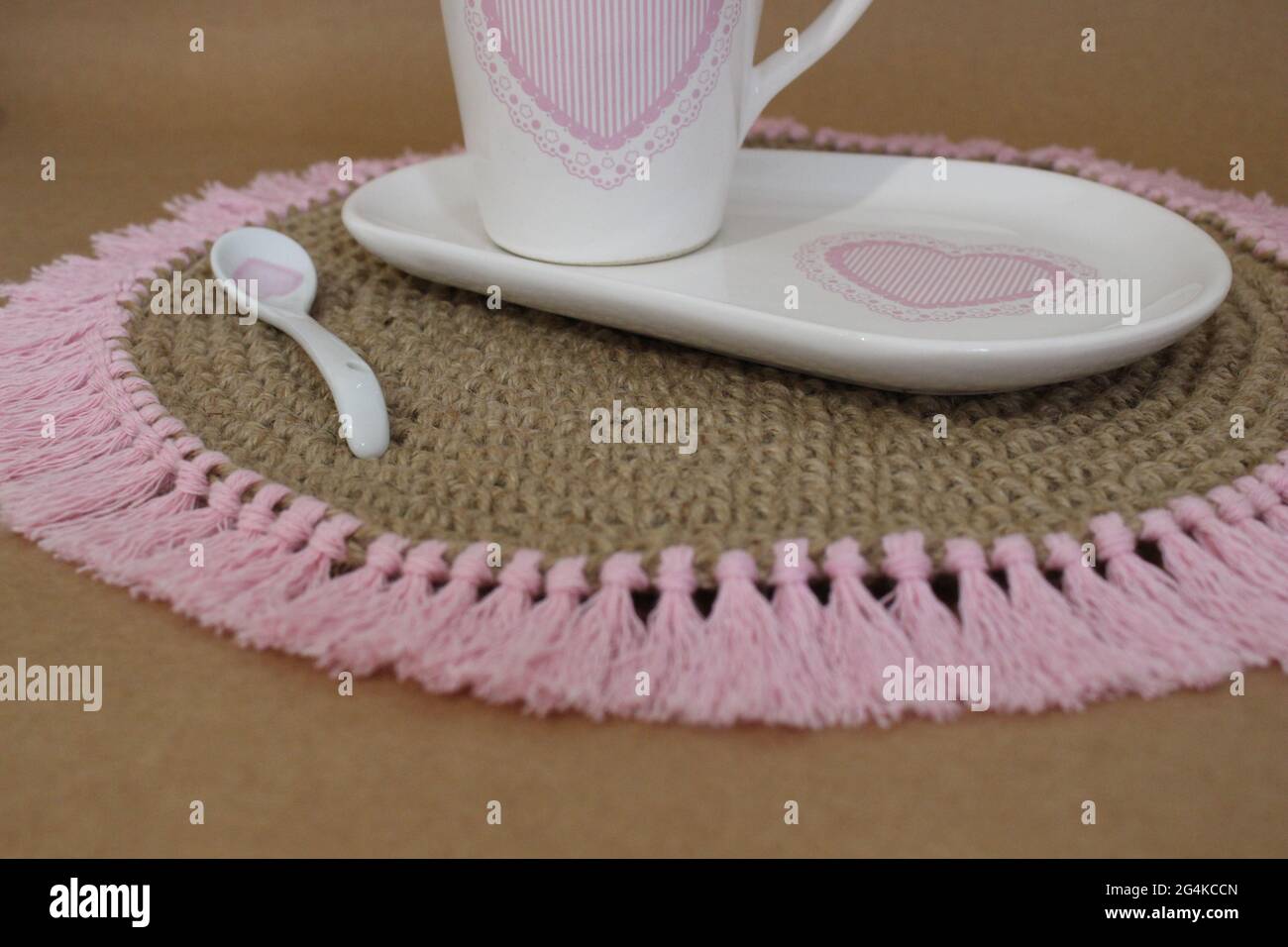 A closeup shot of a brown knit placemat with pink tassels Stock Photo