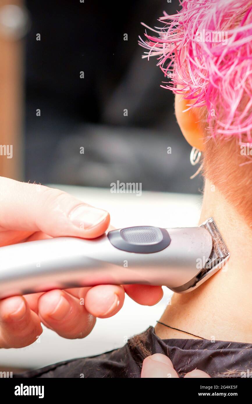 Back view of hairdresser's hand shaving nape and neck with electric trimmer  of young caucasian woman with short pink hair in beauty salon Stock Photo -  Alamy