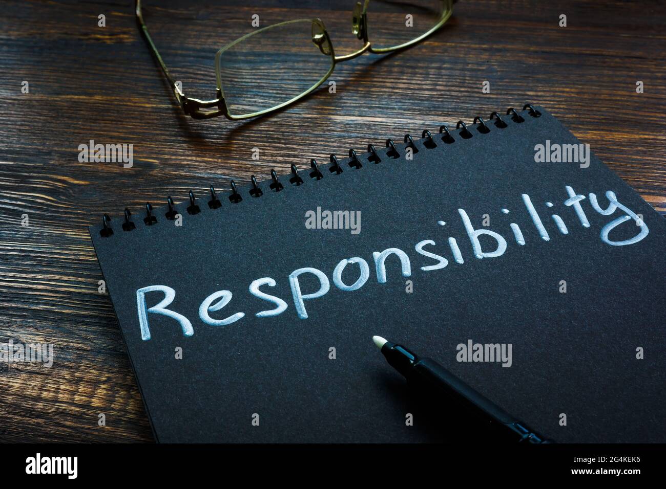 Responsibility word handwritten on the black page. Stock Photo