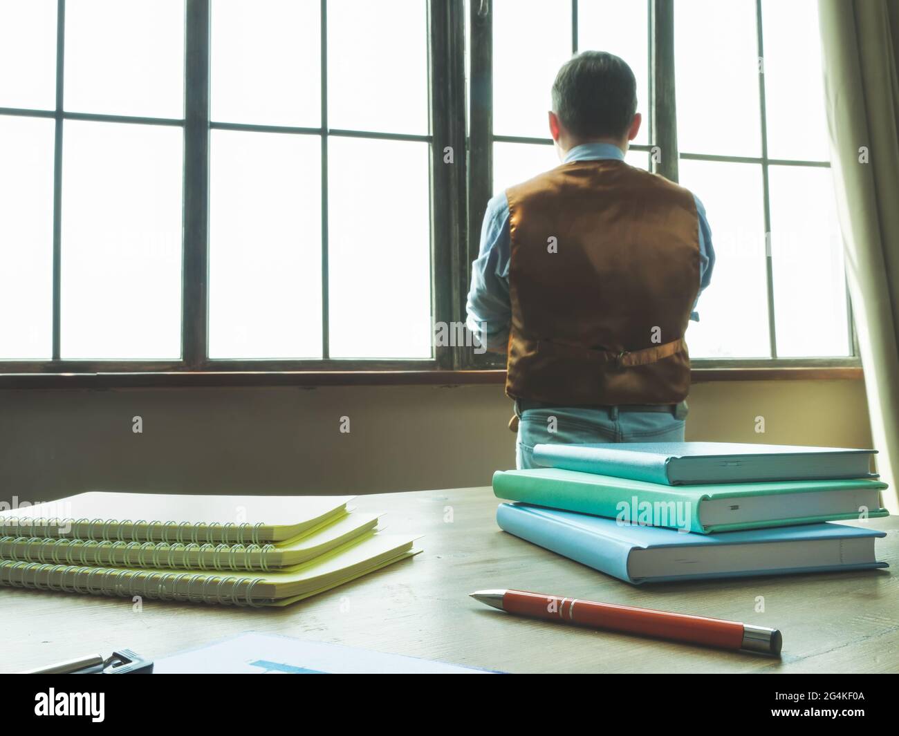 The man in the office looks out the window. The businessman is pondering. Stock Photo