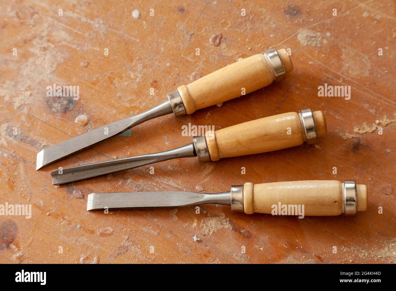 A set of three wood chisels on a dusty bench Stock Photo