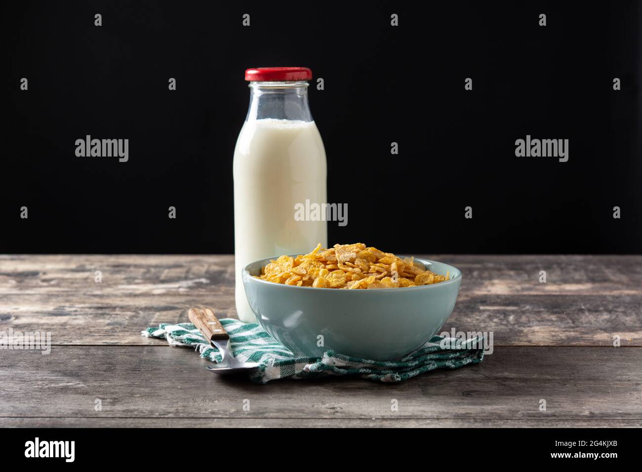 Corn flakes in a blue bowl and milk bottle on wooden table Stock Photo