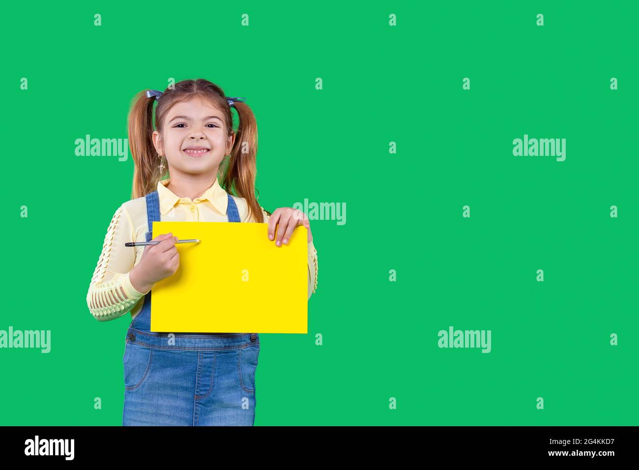 A girl is holding a pencil in her arms and a paper of a yellow color ...