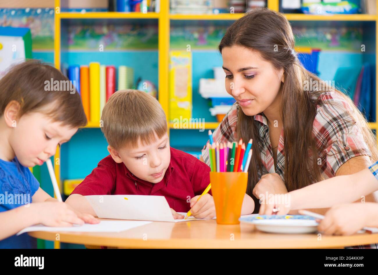 Cute little children drawing with teacher at preschool class Stock