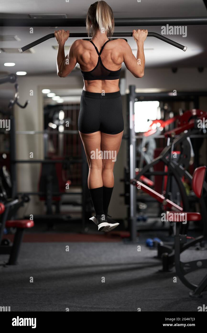 Fitness woman doing chin-ups in the gym for back workout Stock