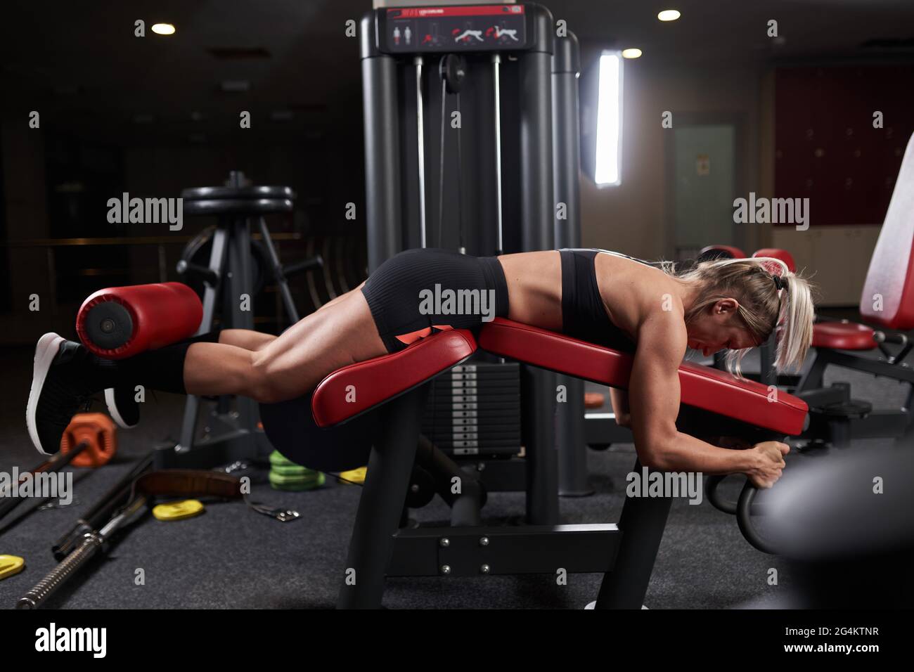 Fitness woman doing leg curls at the press machine in the gym Stock Photo