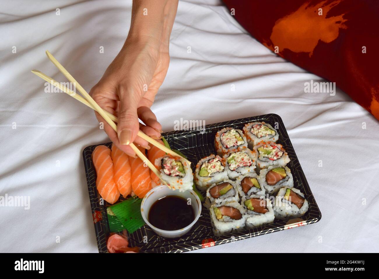 Lady is eating sushi with chopsticks Stock Photo