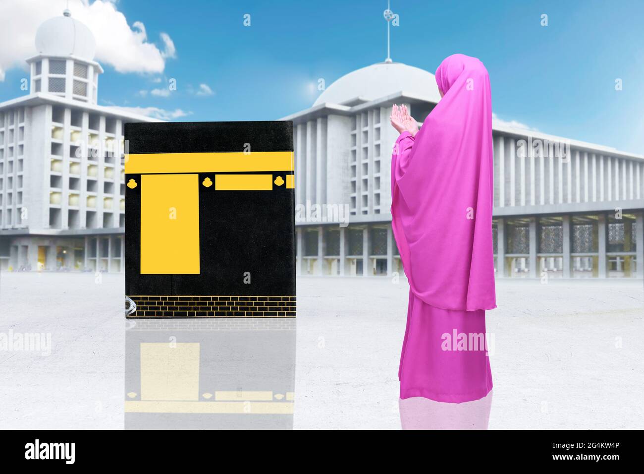 Rear view of Asian Muslim woman in a veil standing and praying with ...