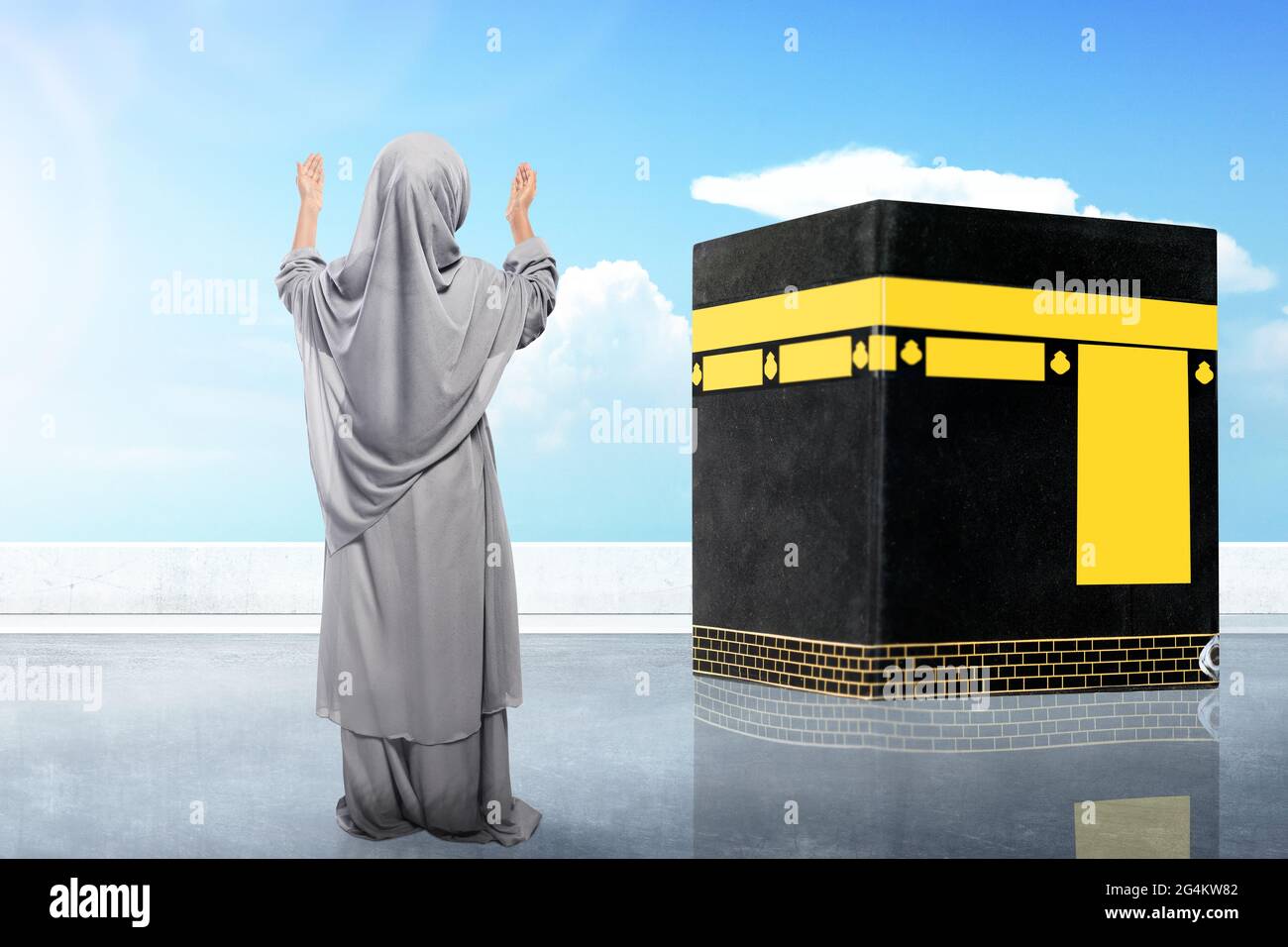 Rear view of Asian Muslim little girl in a veil standing and raised ...
