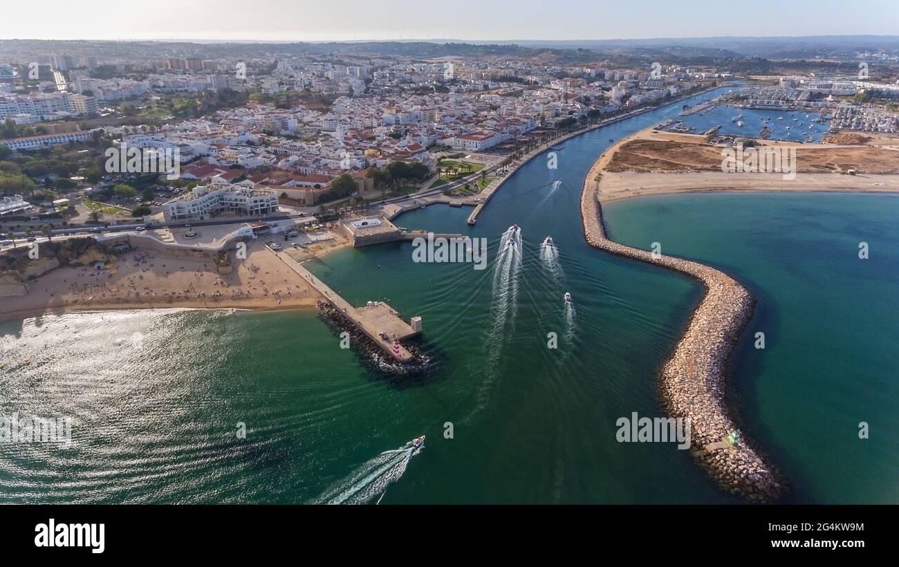 Aerial view from the sky of the Portuguese coastline of the Algarve zone of Lagos city. Boats and ships are moving in the direction of the port. Stock Photo