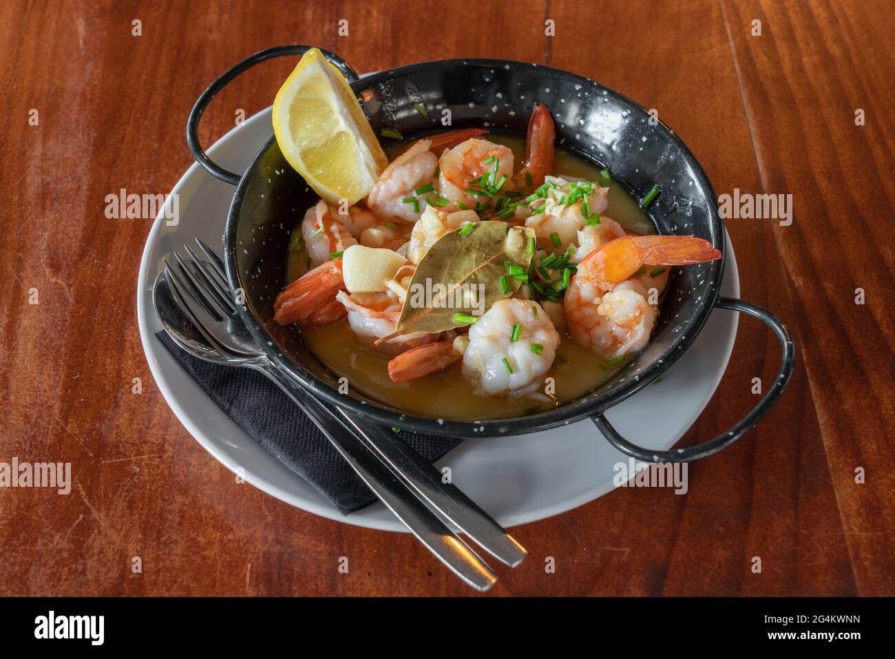 Shrimps in a metal plate stewed in sauce with a slice of lemon. Traditional Portuguese cuisine. Mediterranean Culture. Top view. Stock Photo