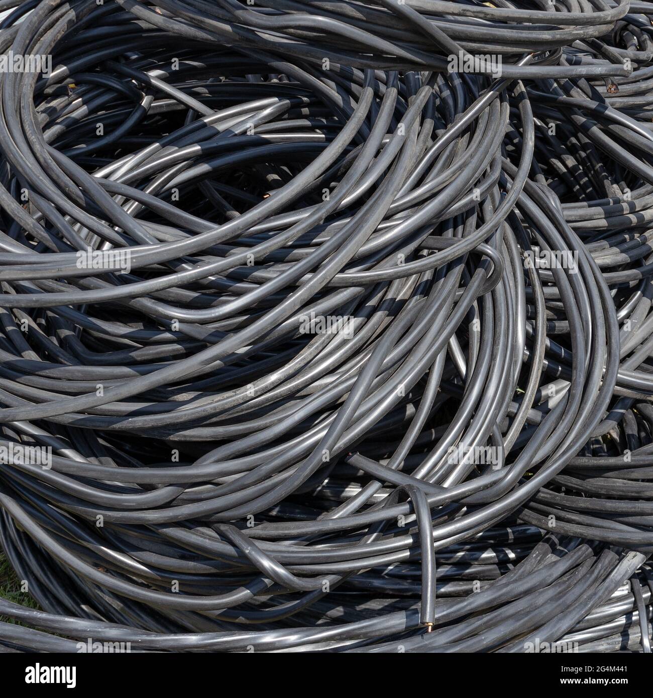 A twisted copper wire in black plastic insulation lies in a pile. Electrification and automation of systems. Consumable material. Stock Photo
