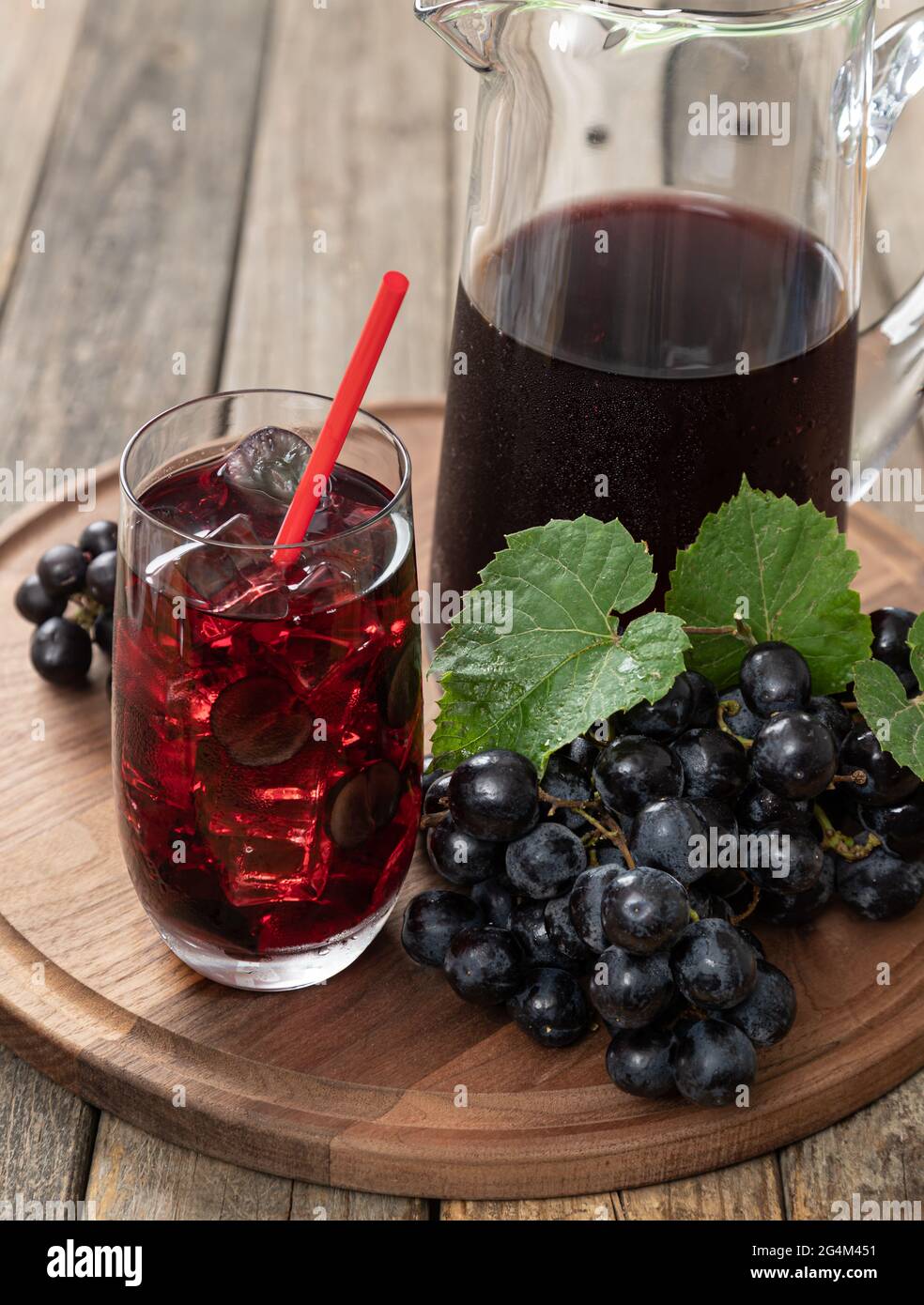 Glass of grape juice with fresh grapes and pitcher on a rustic wooden