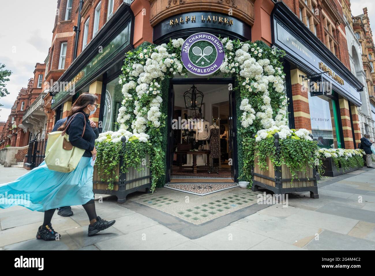 London, UK. 22 June 2021. A woman walks past the exterior of the Ralph  Lauren store in Sloane Square, decorated ahead of this year's upcoming  Wimbledon tennis championships at the All England