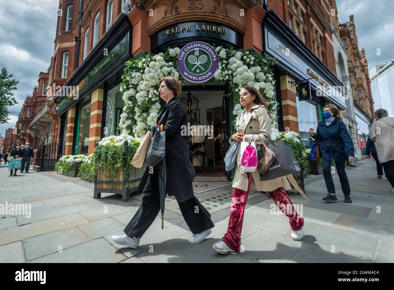 London, UK.  22 June 2021.  Women walk past the exterior of the Ralph Lauren store in Sloane Square, decorated ahead of this year’s upcoming Wimbledon tennis championships at the All England club. Ralph Lauren supplies outfits for officials at the event.  Lockdown restrictions will limit crowds, but the finals will be at full capacity when restrictions are relaxed.  Credit: Stephen Chung / Alamy Live News Stock Photo