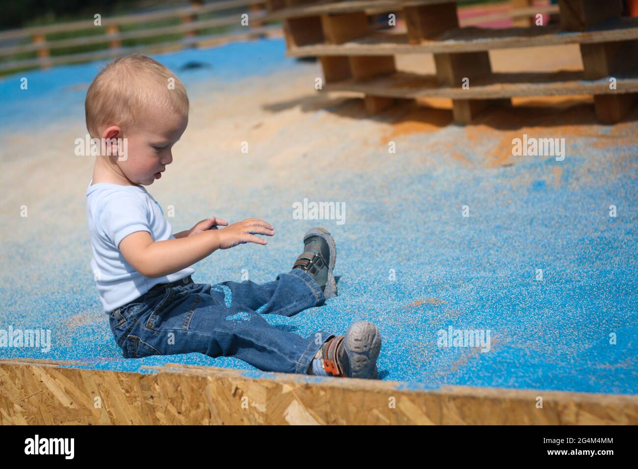 One year old baby boy play in sandpit with blue sand Stock Photo Alamy