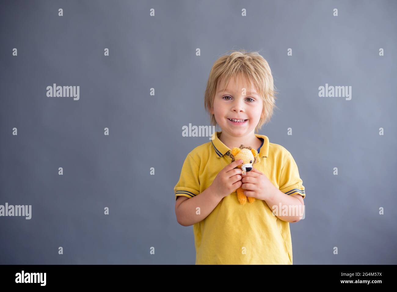 Little toddler child, blond boy, playing with handmade little stuffed knitted toy Stock Photo