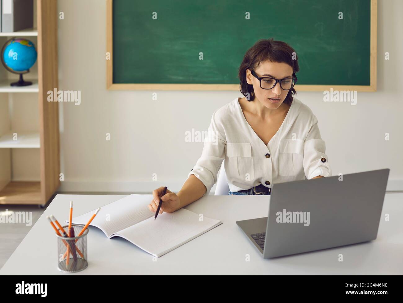 Teacher Using Computer And Desk