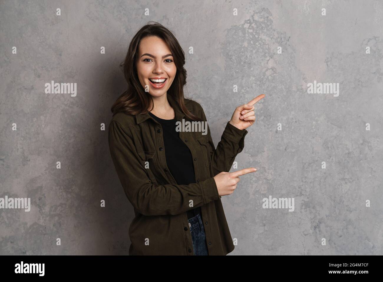 Happy beautiful brunette girl smiling and pointing fingers aside ...
