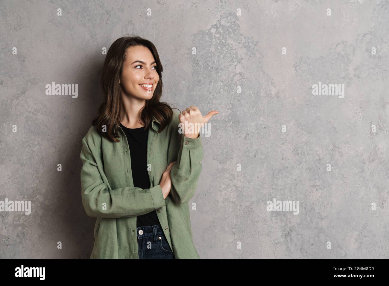 Happy beautiful brunette girl smiling and pointing finger aside ...