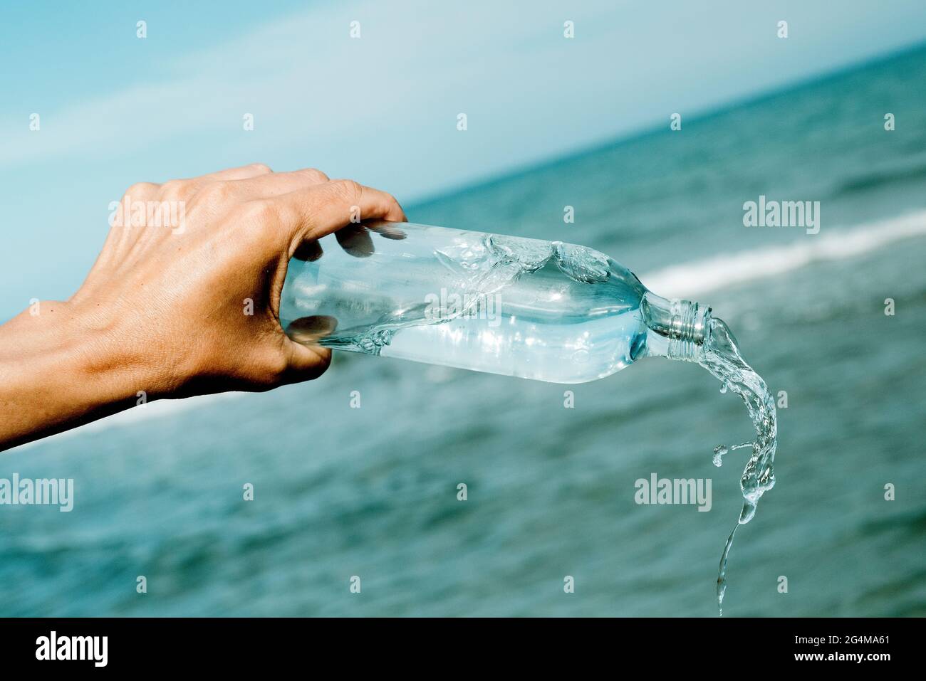 https://c8.alamy.com/comp/2G4MA61/a-young-caucasian-man-pours-water-from-a-glass-reusable-water-bottle-in-front-of-the-ocean-2G4MA61.jpg