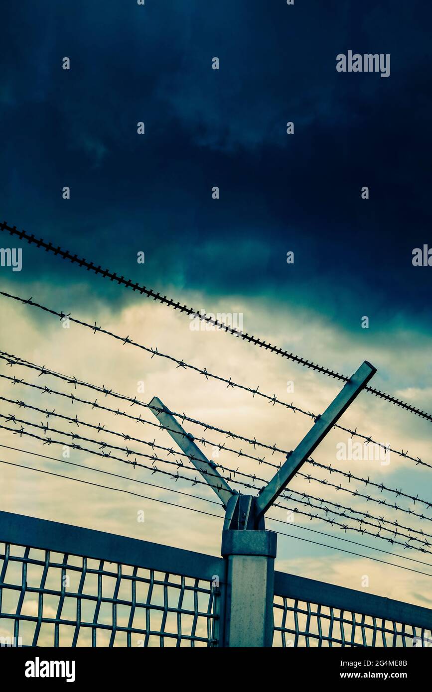 Barbed wire fence in front of dark clouds Stock Photo