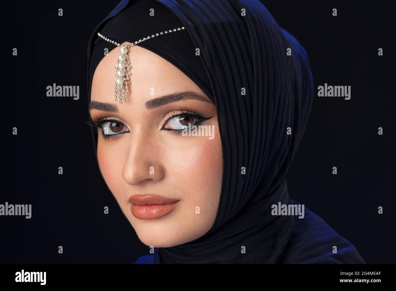 Portrait of a young muslim woman in hijab on black background Stock