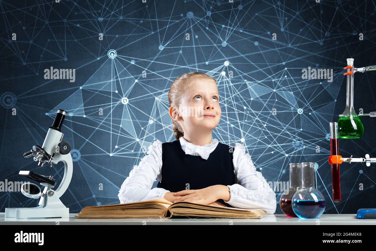 Smiling little girl sitting at desk with open book Stock Photo - Alamy
