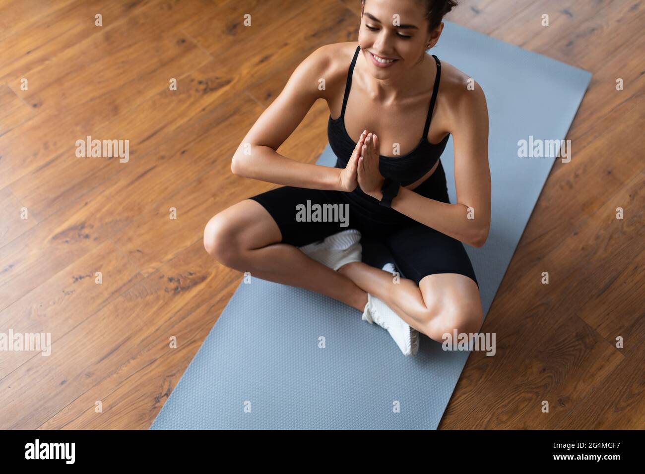 Attractive young woman sitting on lotus position on floor mat Stock Photo
