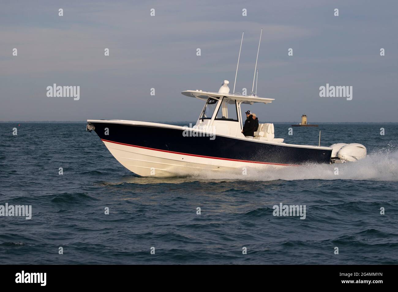 A center console boat cruising on a lake with a lighthouse in the background. Stock Photo
