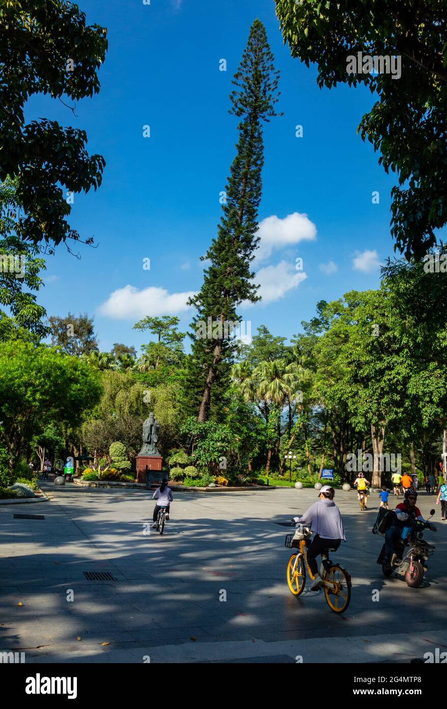 Entrance to Donghu Park with leaning tree and people moving in and out in Shenzhen, China Stock Photo