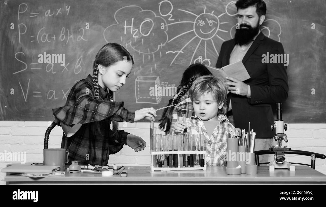 doing experiments with liquids in chemistry lab. chemistry lab. happy children and teacher. back to school. kids in lab coat learning chemistry in Stock Photo