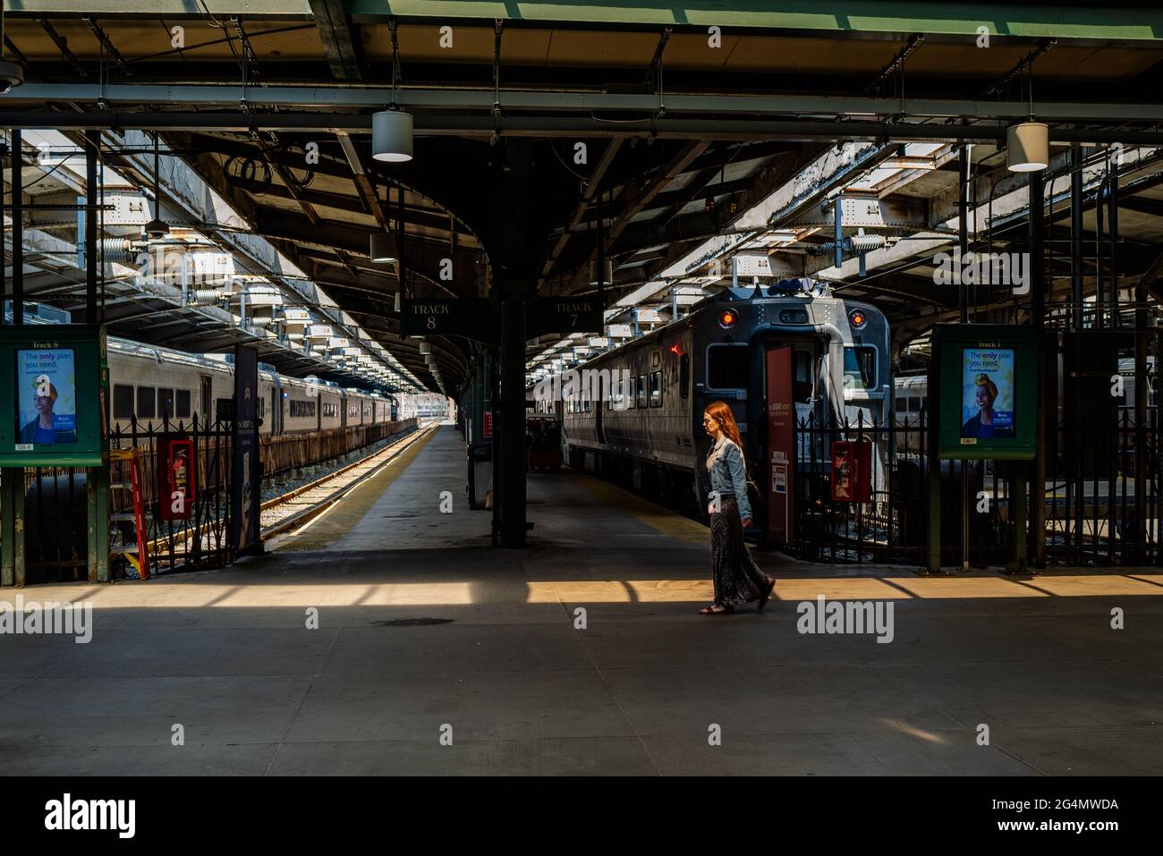 Hoboken, NJ, USA — June 19, 2021. A red headed woman walks in a streak of light in the Hoboken train station in New Jersey. Stock Photo