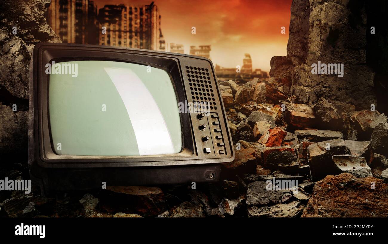 Photo of old fashioned tv set laying on pile of bricks on ruined city wasteland background. Stock Photo