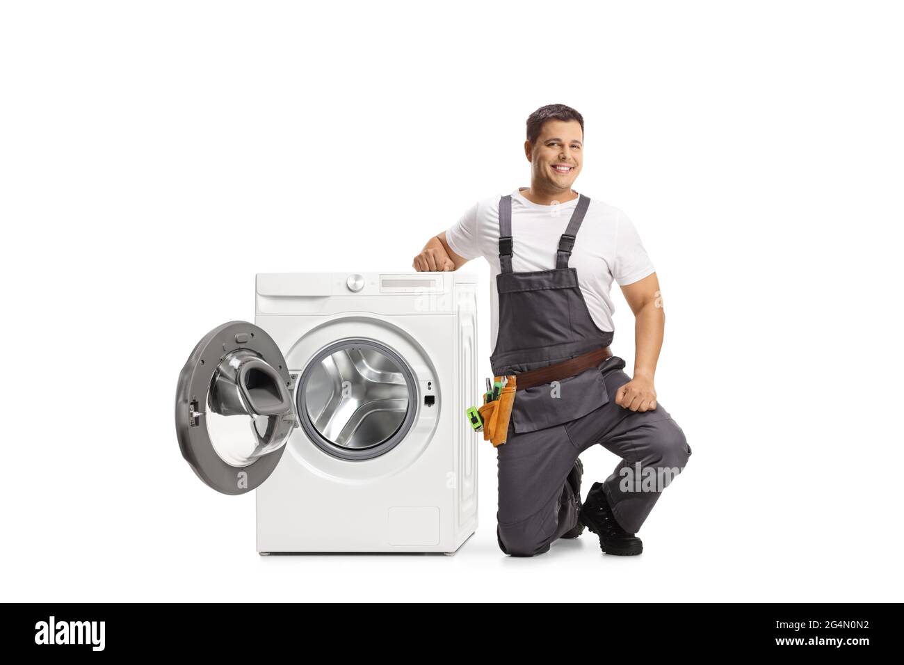 Repairman kneeling next to a washing machine and looking at camera