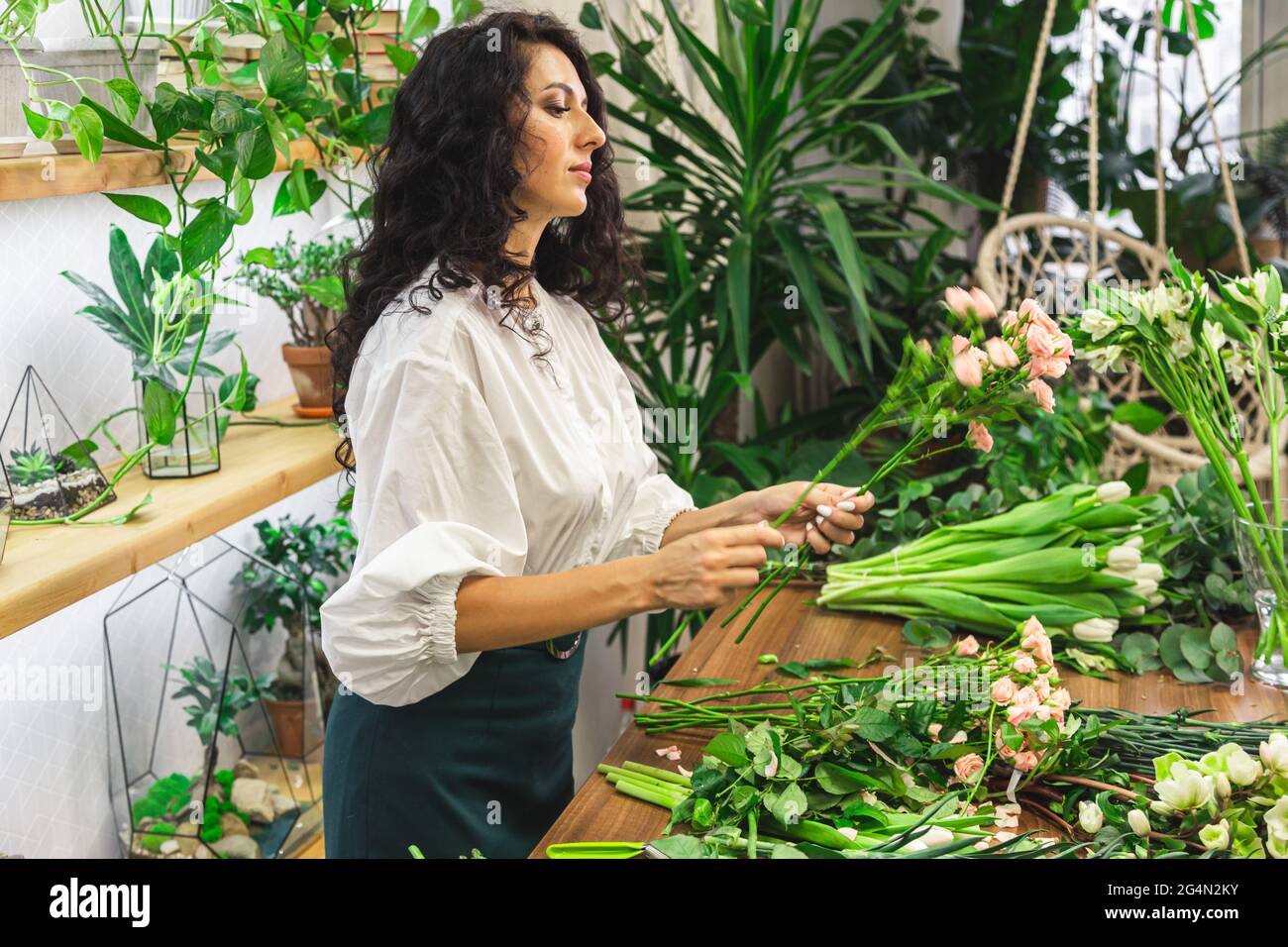 Attractive young woman florist is working in a flower shop Stock Photo ...