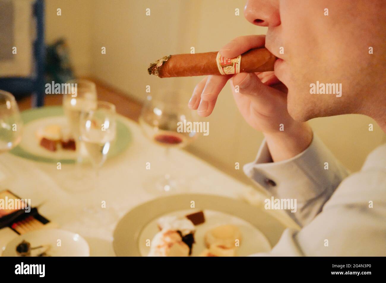 Italian man smokes a cigar after finishing red wine dinner Stock Photo