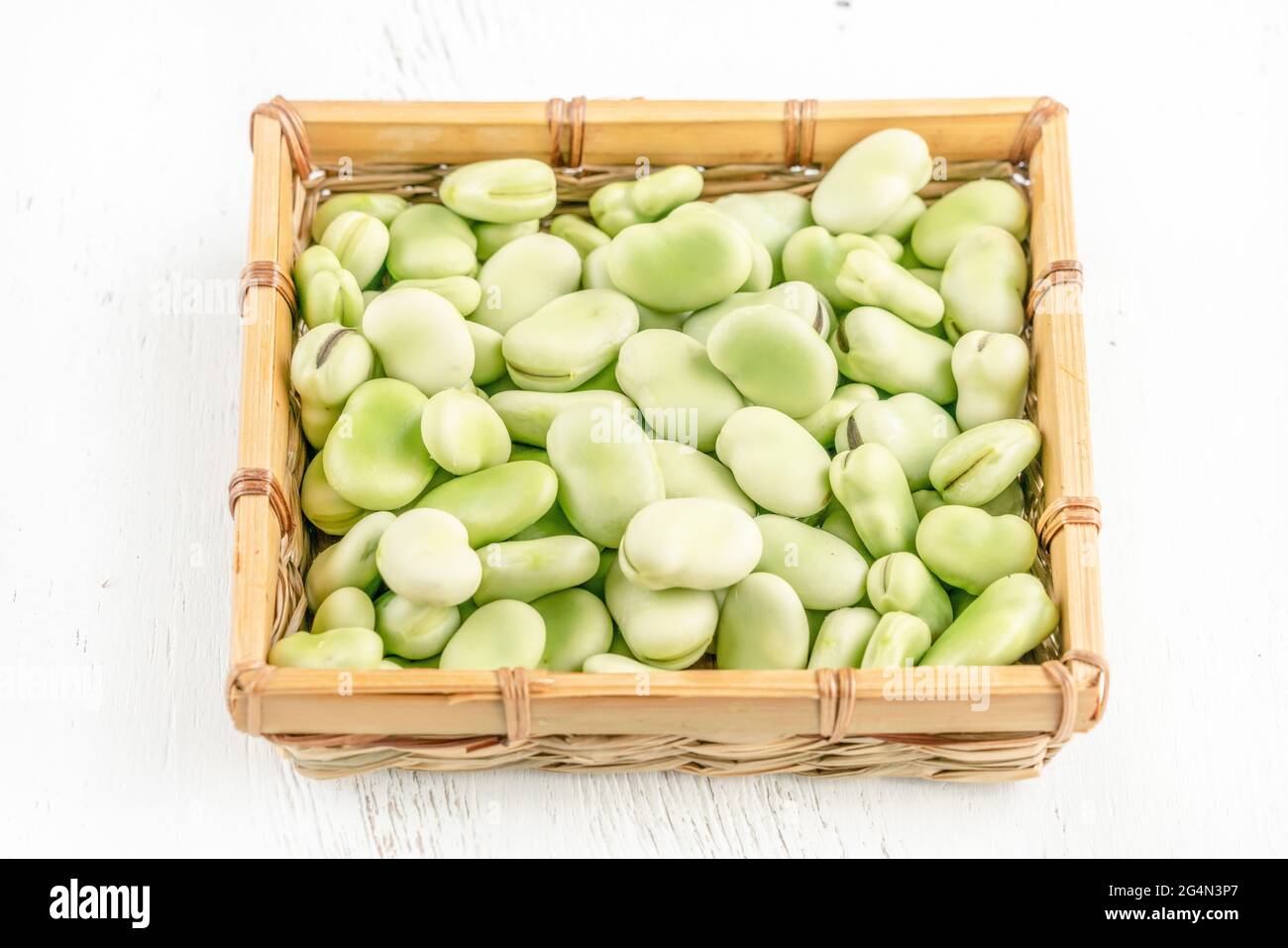closeup fresh broad bean seeds in a basket on a wooden table Stock Photo