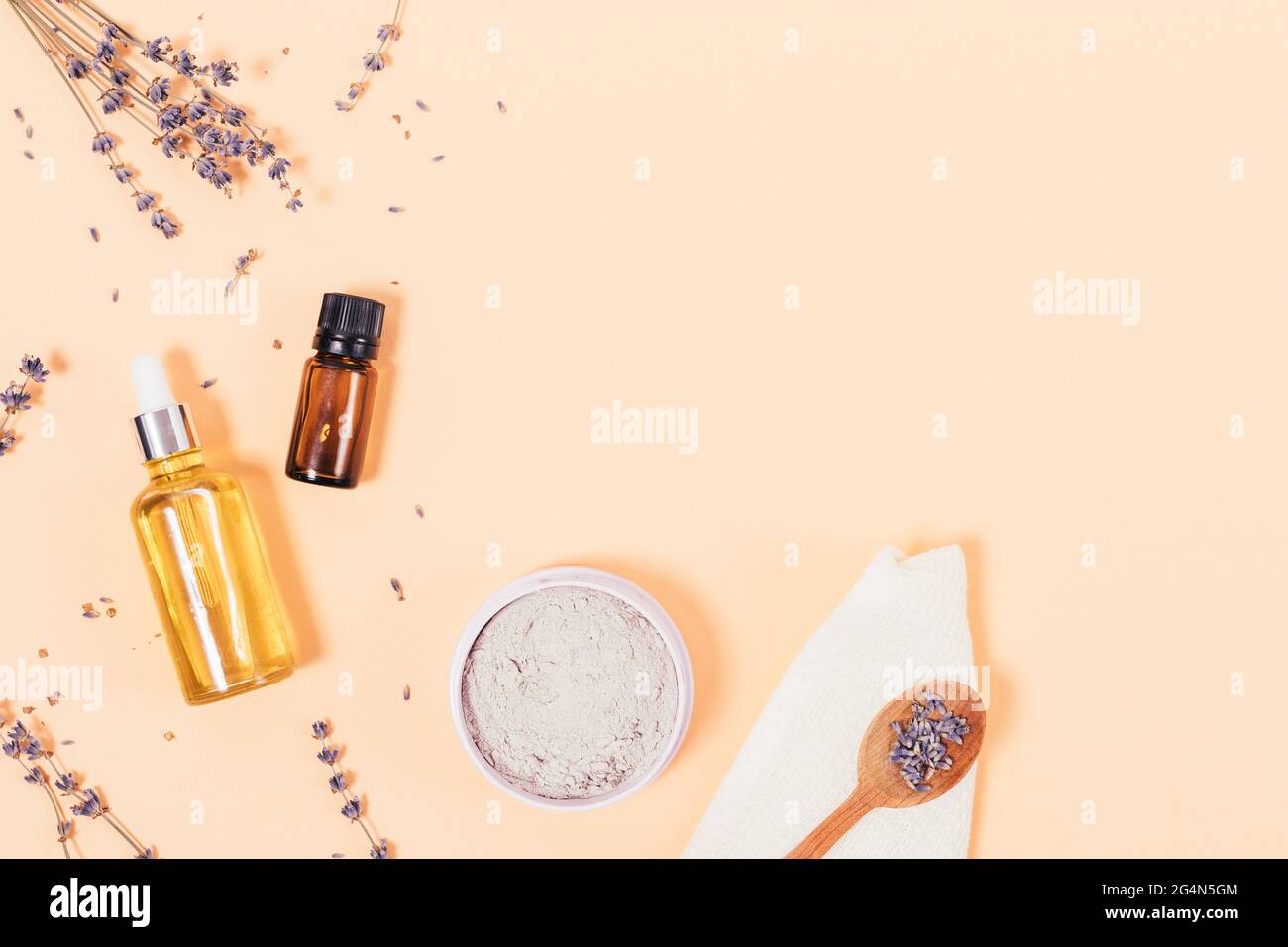 Flat lay composition with lavender flowers, cosmetic clay and aroma oil ingredients for home beauty treatments, beige background with copy space. Stock Photo