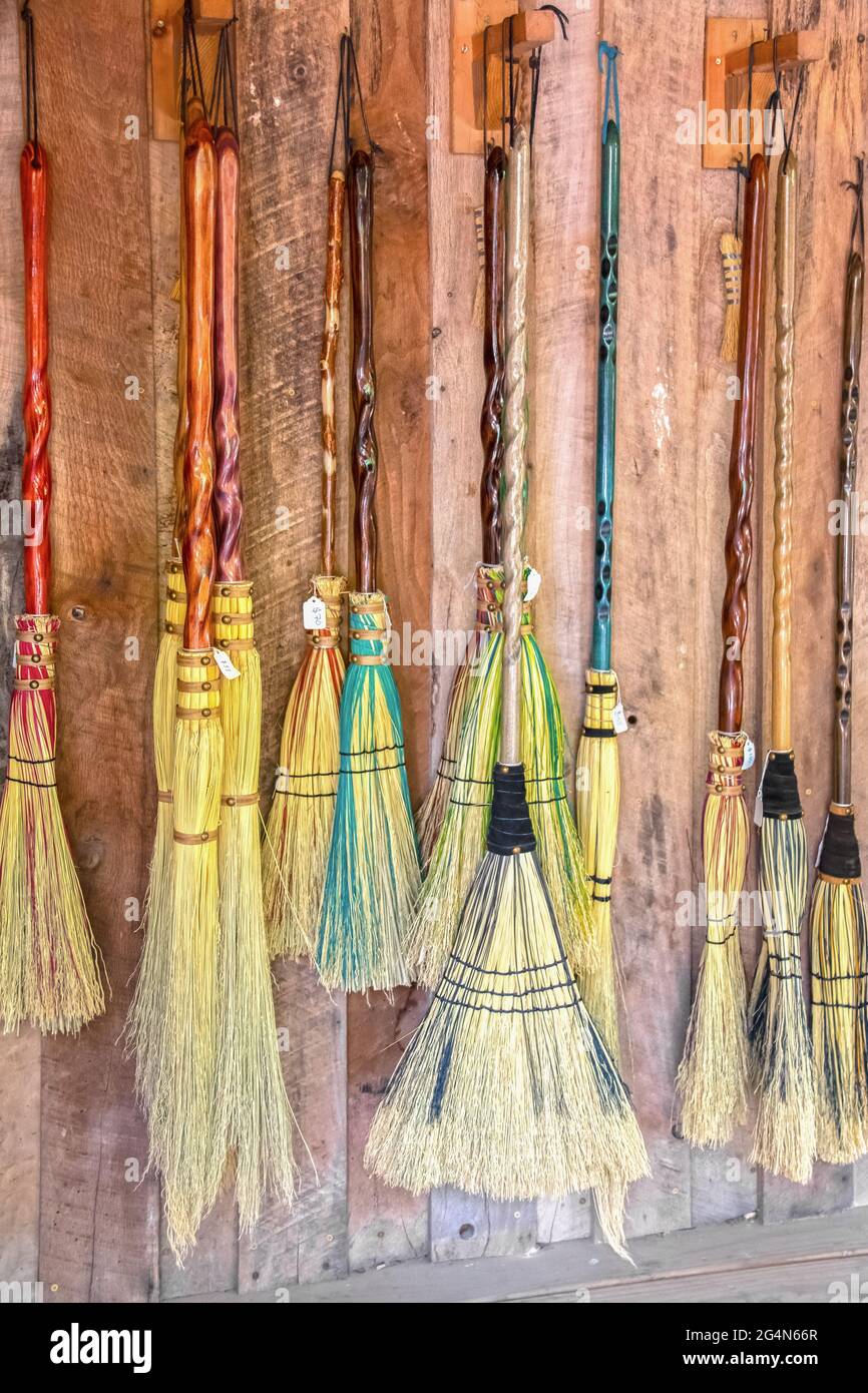 Brooms for sale - variety of decorative brooms that look like they are made for witches and wizards and flying hanging against wooden wall with price Stock Photo
