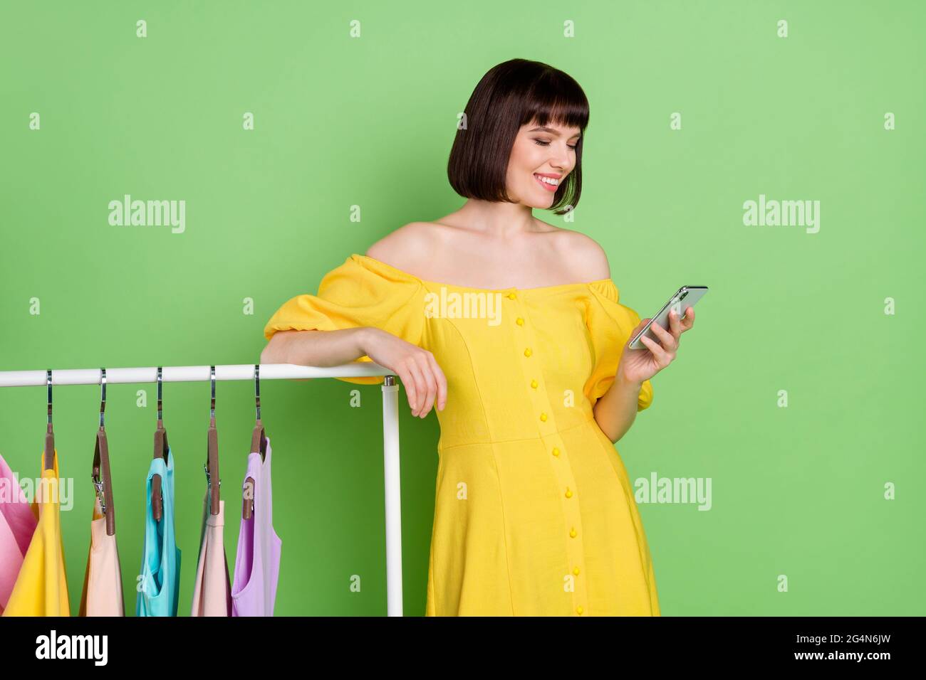 Photo of cheerful young nice brunette bob haired woman wear yellow dress  look phone showroom isolated on green color background Stock Photo - Alamy