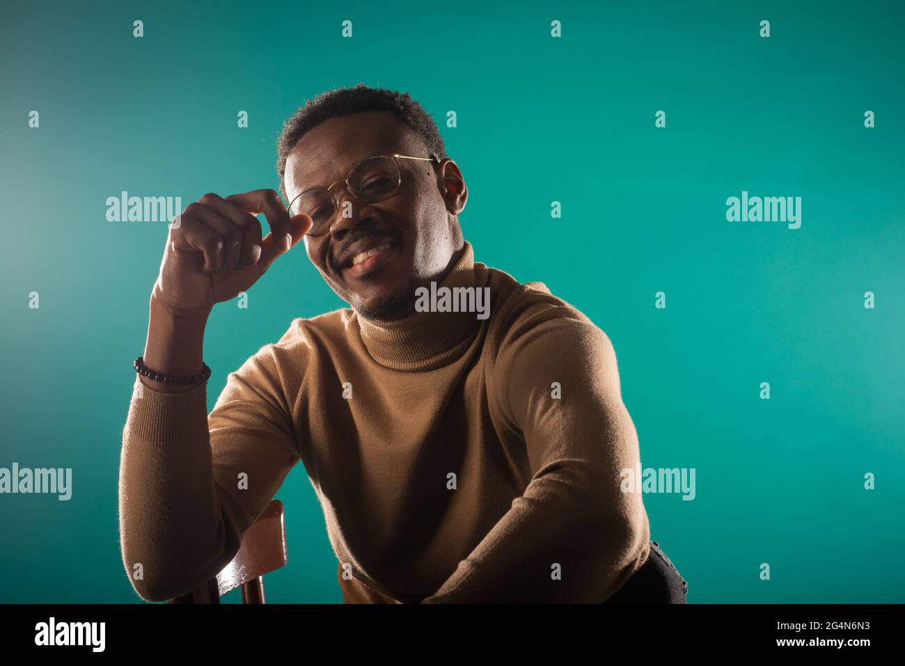 Handsome black male is smiling while posing on the chair Stock Photo