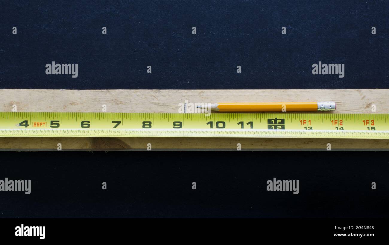 A Tape Measure, Pencil and a Piece of Wood Marked to be Cut Stock Photo