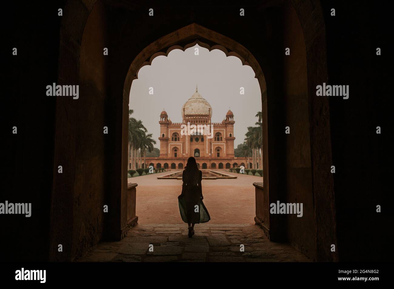 Full body back view silhouette of anonymous female tourist admiring historic building of Safdarjungs Tomb in New Delhi Stock Photo