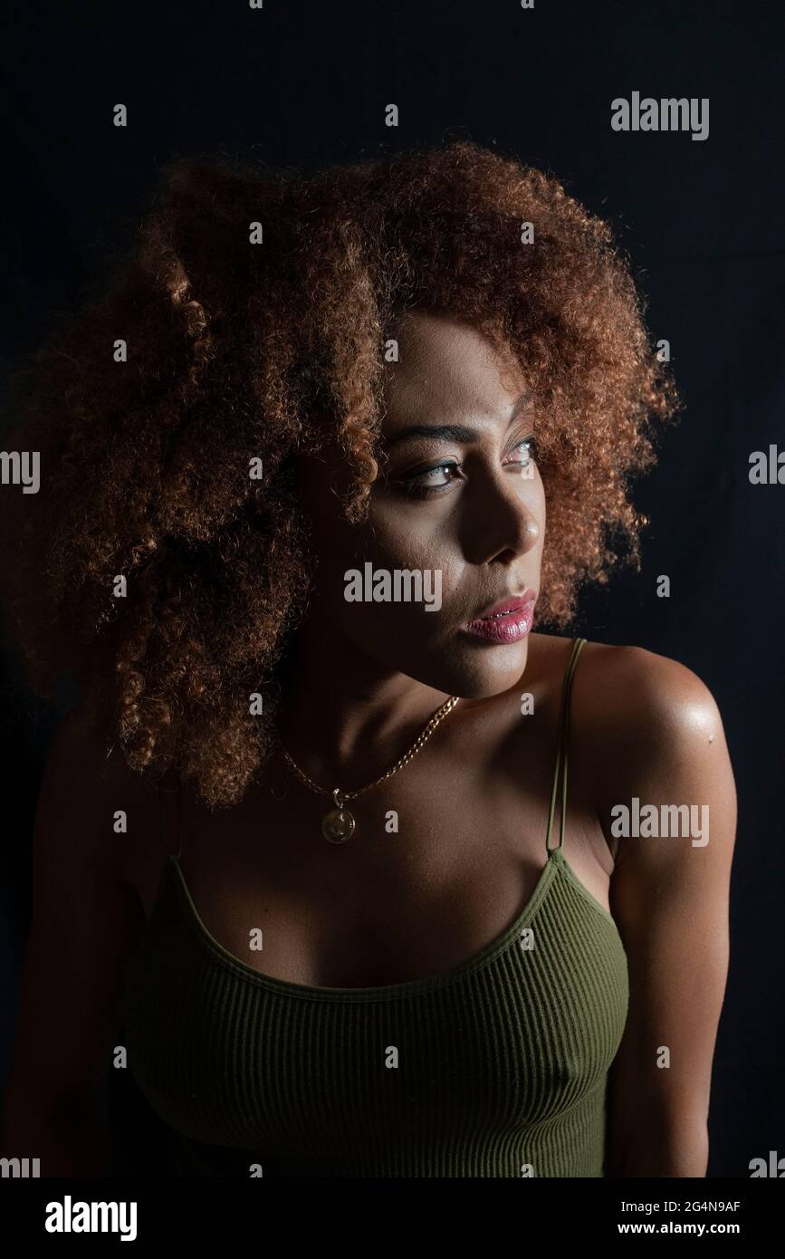 Charming African American female model with curly hair looking away in ...