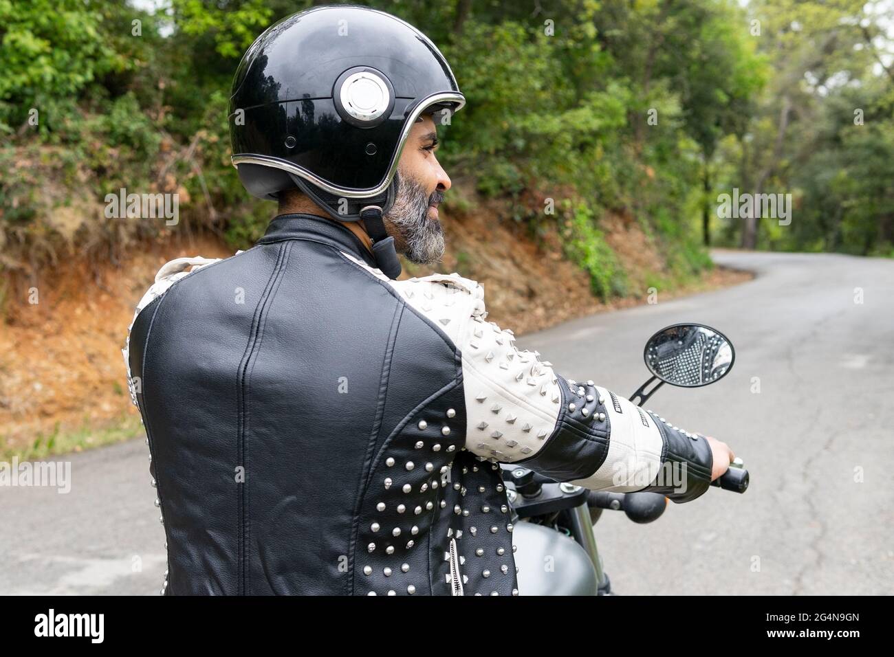 Back view bearded ethnic male biker in black leather jacket and helmet ...