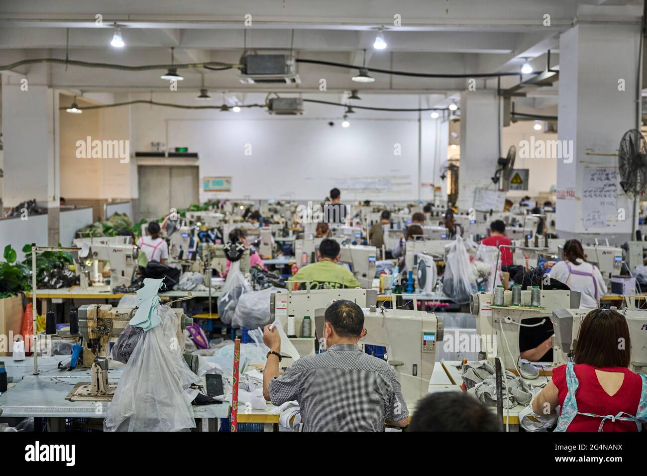 View of busy sewing room in Chinese shoes factory Stock Photo