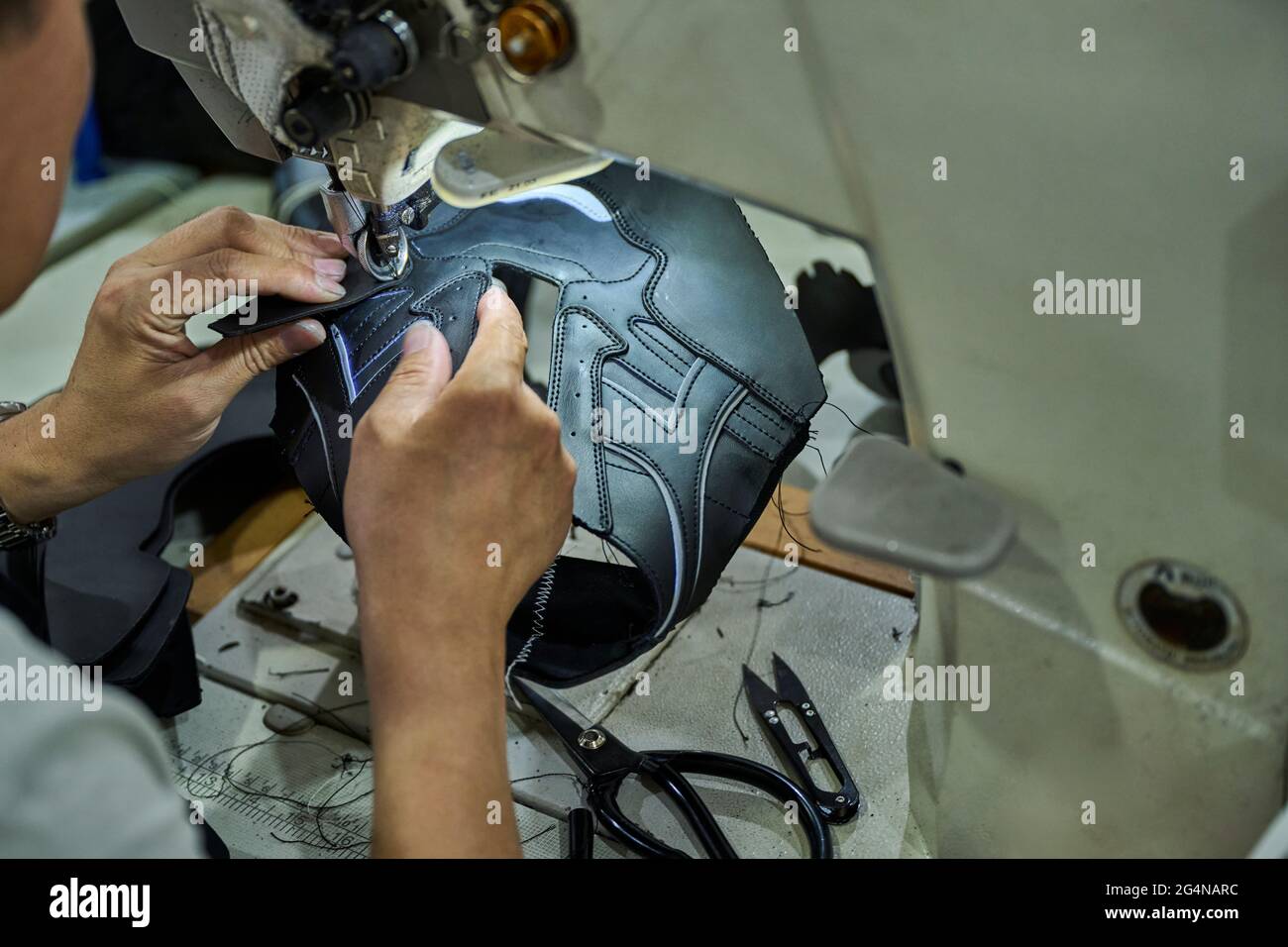 Detail of worker's hands doing sewing in the leather of the shoes at Chinese shoes factory Stock Photo