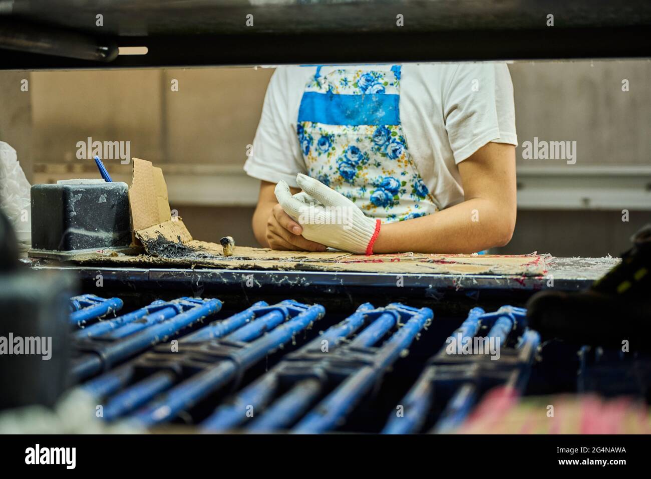 Detail of worker applying glue to the shoes sole in a production line of Chinese shoes factory Stock Photo